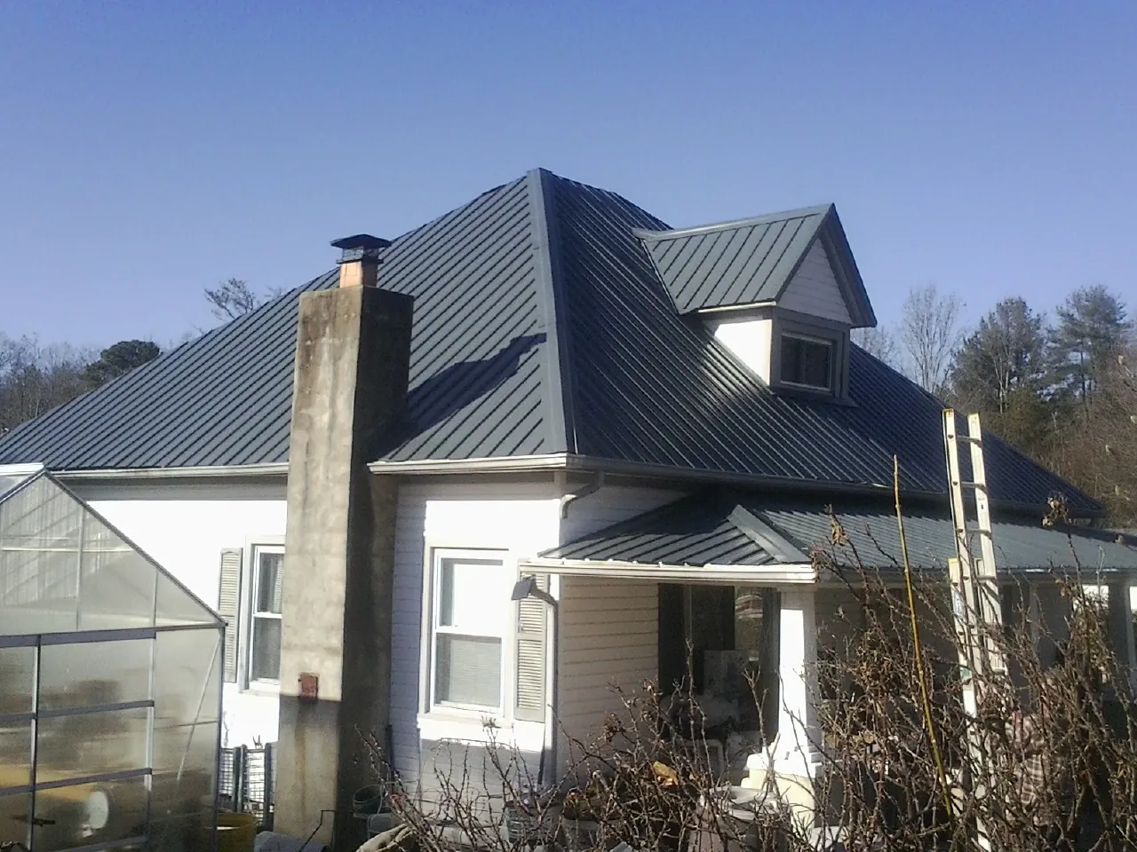 Dark blue standing seam metal roof on a white farmhouse with dormer — Slate & Tile Roof Repair by Roofing Brothers in West Nyack