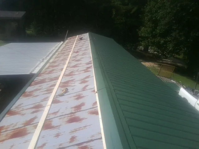 Old rusted panels beside newly installed green metal roofing — Wind Damage Roof Repair by Roofing Brothers in West Nyack