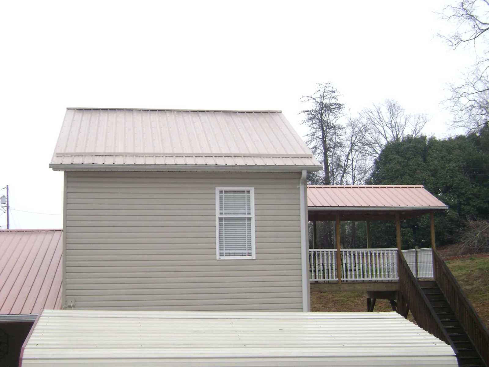 Tan metal roofs on a two story addition and attached porch, from a Roof Replacement job in West Nyack