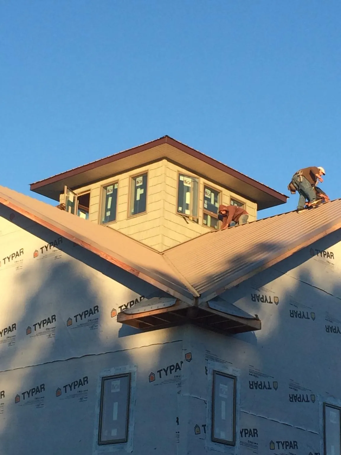 Roofers working around a rooftop cupola on a new metal roof at sunset — Roof Waterproofing in West Nyack by Roofing Brothers